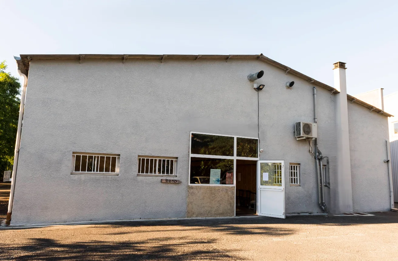 Le bâtiment du Dojo Kaizen, façade claire à porte vitrée, vu depuis le parking