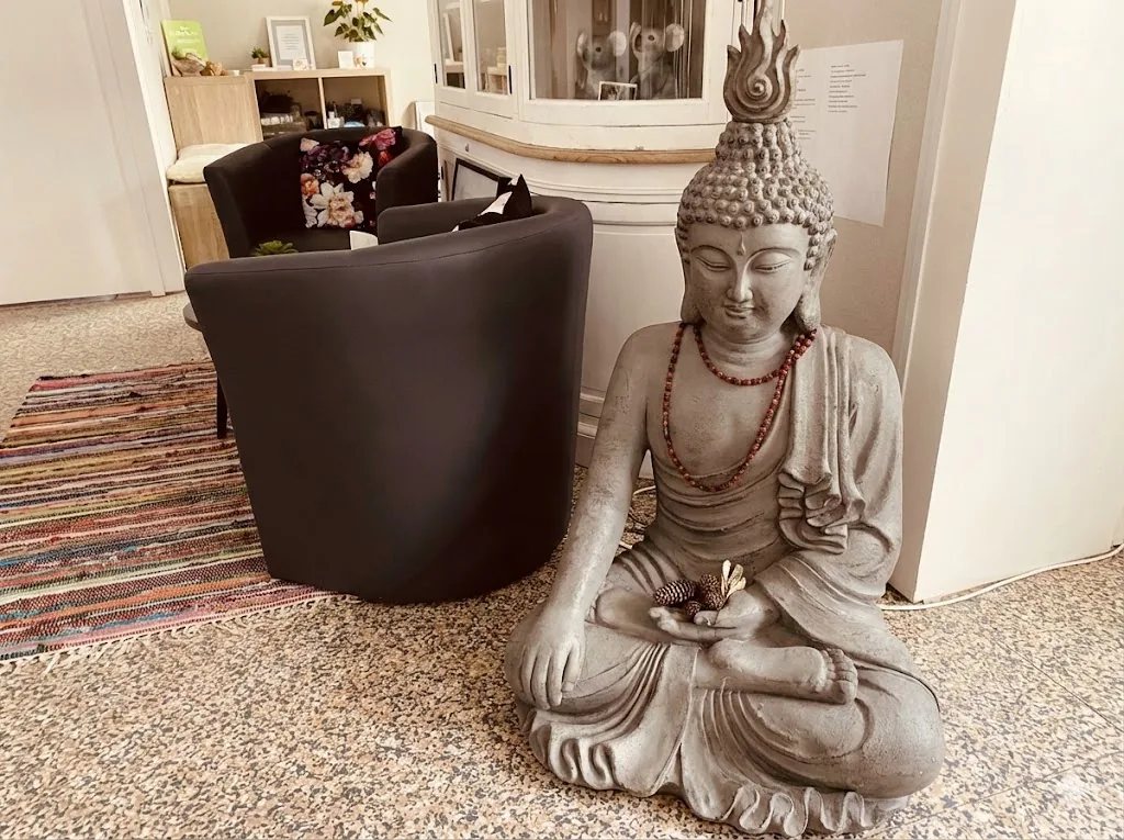 La salle d'attente : fauteuils bas, tapis tissé et statue de Bouddha en pierre